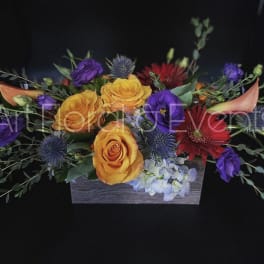 Colorful floral arrangement in a rectangular wooden box with roses and calla lilies