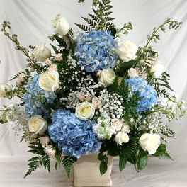 Blue hydrangeas and white roses in a cream vase