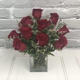 Red roses arranged in a clear square glass vase