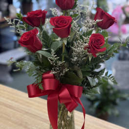 Red roses arranged in a clear glass vase with a red ribbon