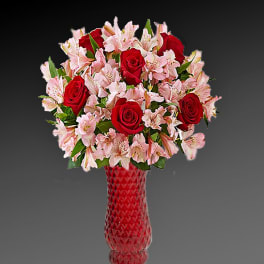 Red roses and pink lilies in a red glass vase
