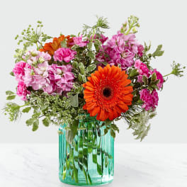 Pink and orange mixed bouquet in a turquoise glass vase