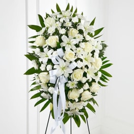 White floral standing spray with roses and lilies on an easel