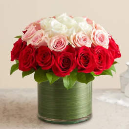 Red, pink, and white roses arranged in a green glass vase