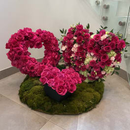 Pair of pink rose heart arrangements on a moss-covered base