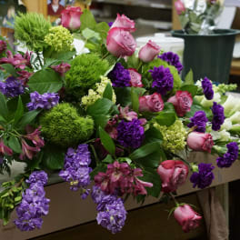 Mixed bouquet with pink roses, purple flowers, and green pom-pom blooms