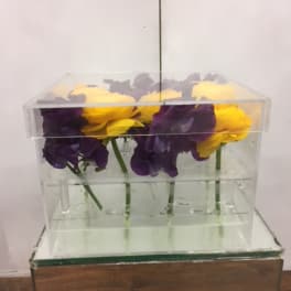 Purple and yellow flowers arranged in a clear acrylic box