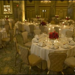 Round banquet tables with red floral centerpieces and candles in a formal hall