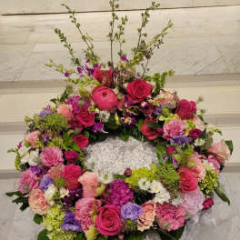 Large pink and purple floral wreath on a lace-covered stand