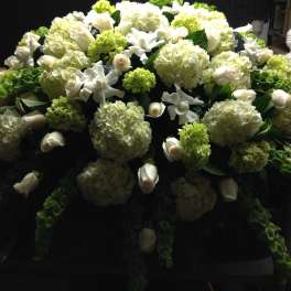 Large white floral casket spray with hydrangeas, roses, and calla lilies