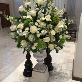 Large white floral arrangement in a pedestal urn
