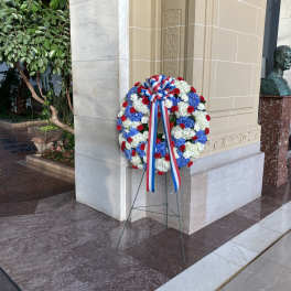 Large red, white, and blue floral wreath on a stand with ribbon