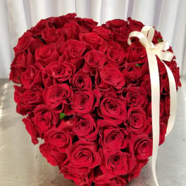 Heart-shaped bouquet of red roses with a white ribbon