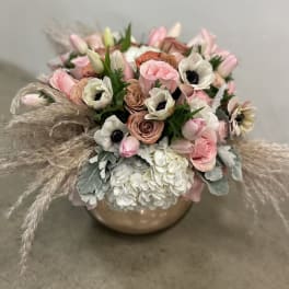 Low bowl arrangement of pink roses, white hydrangeas, anemones, tulips, and pampas plumes