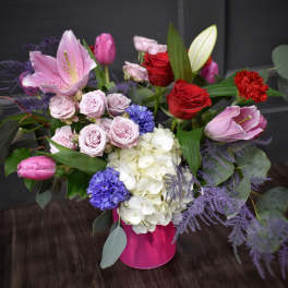 Mixed bouquet with pink lilies, red roses, and white hydrangeas in a pink vase