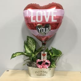 Heart-shaped LOVE balloon above potted plants in a decorative container