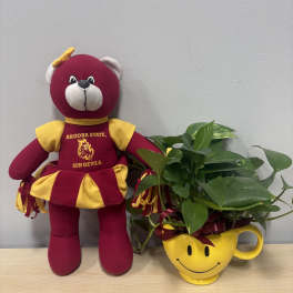 Plush bear beside a leafy plant in a yellow smiley-face mug