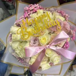 Bouquet of pale roses with a pink ribbon and "Happy Birthday" topper