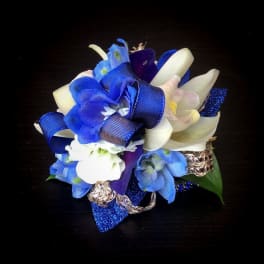 Blue and white floral corsage with ribbon on a dark background