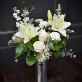 White lilies and roses in a tall silver vase