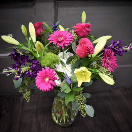 Mixed bouquet of pink roses, lilies, and gerbera daisies in a glass vase