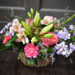 Basket arrangement of pink lilies, roses, and purple flowers