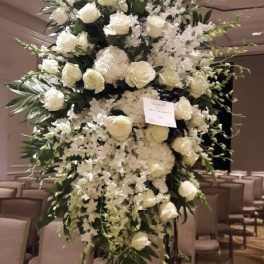 Tall white floral arrangement with roses and orchids on a stand