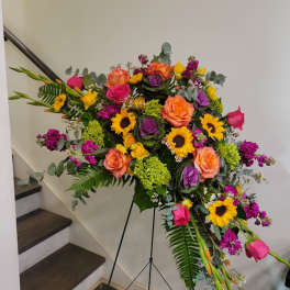 Large standing floral spray with roses, sunflowers, and purple blooms