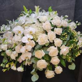White roses and orchids arranged in a large floral spray