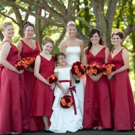 Bridal party in red dresses holding orange and burgundy bouquets