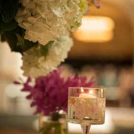 White hydrangea arrangement beside a floating candle in a glass holder