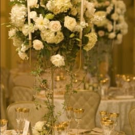 Tall white floral centerpiece on a gold-decorated banquet table