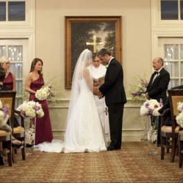 Wedding ceremony with floral aisle arrangements and bridesmaids holding bouquets