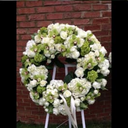 Large white floral wreath with green accents on a stand
