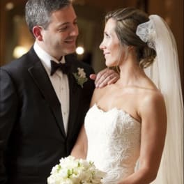 Bride holding a white bouquet beside a groom in a tuxedo