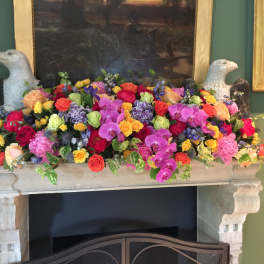 Colorful mixed floral arrangement on a mantel with two bird sculptures