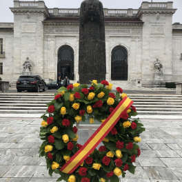 Circular wreath of red and yellow roses with a ribbon on a stand