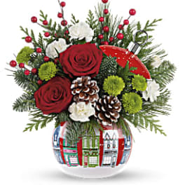 Holiday bouquet with red roses, white blooms, and pinecones in a patterned vase