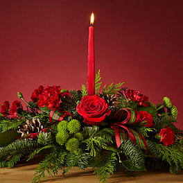 Red floral centerpiece with a lit taper candle and ribbon accents