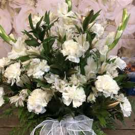 White floral arrangement in a basket with a sheer ribbon bow