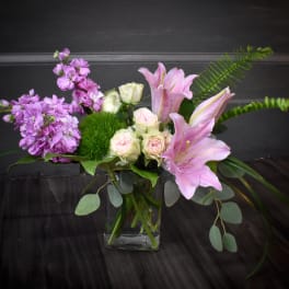 Pink lilies and lavender flowers in a glass vase