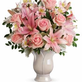 Pink roses and lilies arranged in a white vase