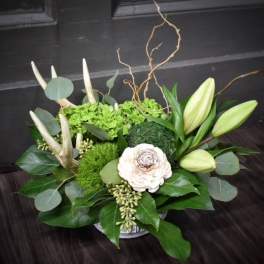 Low floral arrangement with white lilies and a cream bloom in a container