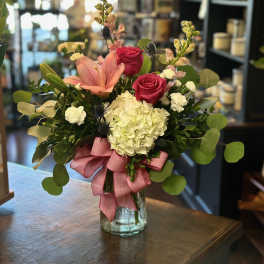 Pink roses and lilies in a glass vase with a pink ribbon
