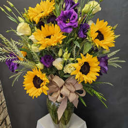 Bouquet of yellow sunflowers and purple lisianthus in a glass vase