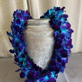 Purple and blue flower lei draped around a silver vase