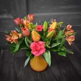 Bouquet of orange tulips, pink carnations, and alstroemeria in a yellow vase