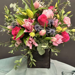 Mixed pink bouquet with roses and lilies in a dark wooden box
