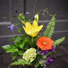 Mixed floral arrangement with yellow lilies and an orange gerbera daisy