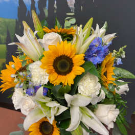 Bouquet of sunflowers, white lilies, and blue flowers in a vase